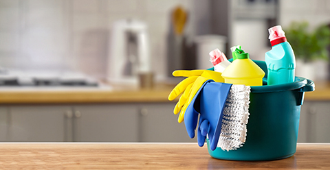 a bucket of cleaning supplies on a wooden countertop in a kitchen area